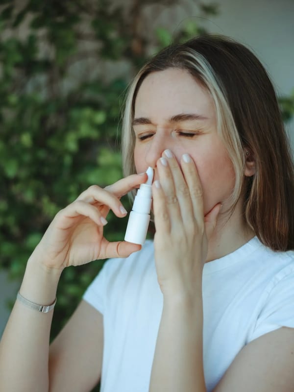 Pharmacist demonstrating proper nasal spray technique